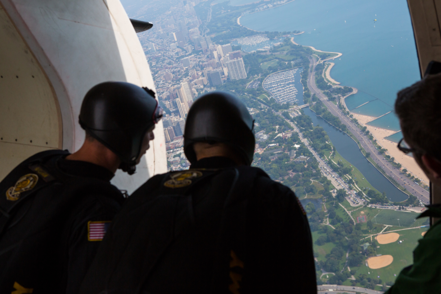 Military parachutists look out of an aircraft over downtown Chicago and Lake Michigan during the Chicago Air and Water Show