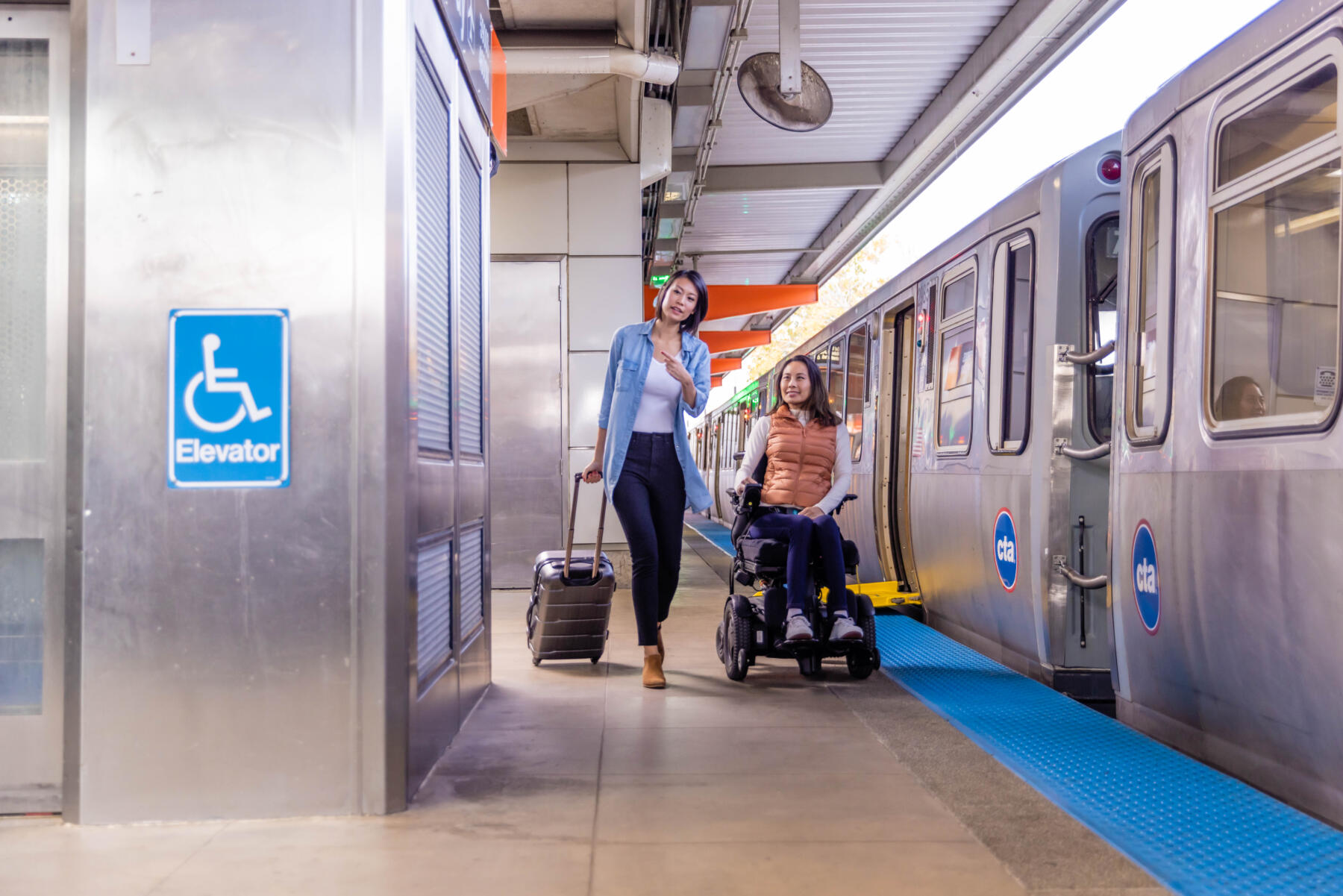 A woman in a wheelchair and her travel companion on a CTA platform in Chicago